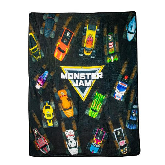 Monster Jam blanket fully expanded, Monster jam logo in the center with monster trucks driving around on the blanket. 